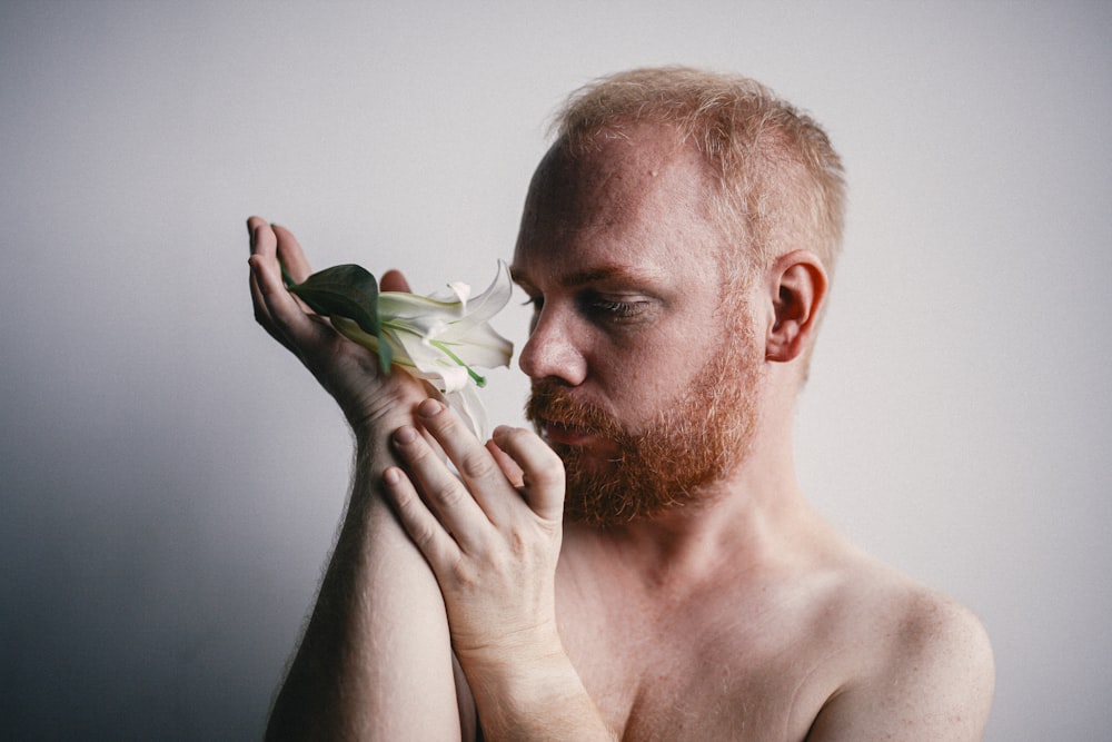 man holding white flower covering his mouth