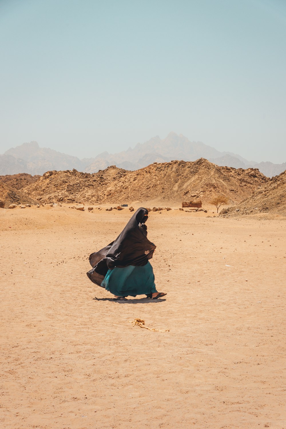 woman in black and green dress sitting on brown sand during daytime