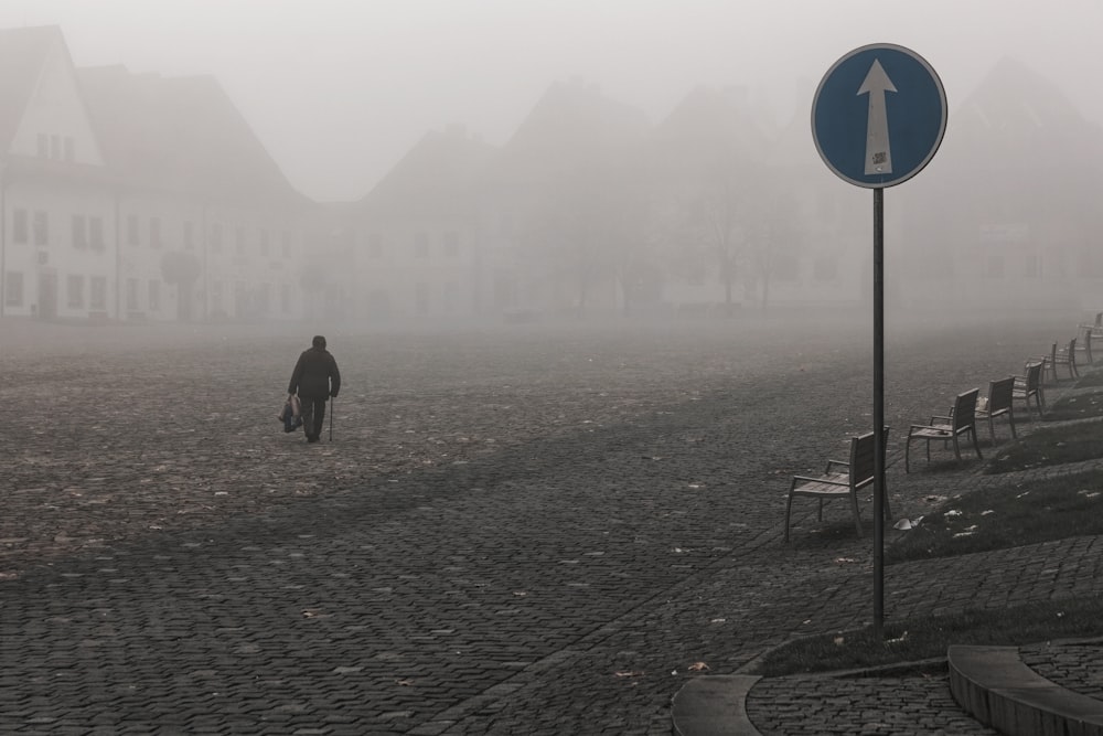 man in black jacket walking on sidewalk during foggy day