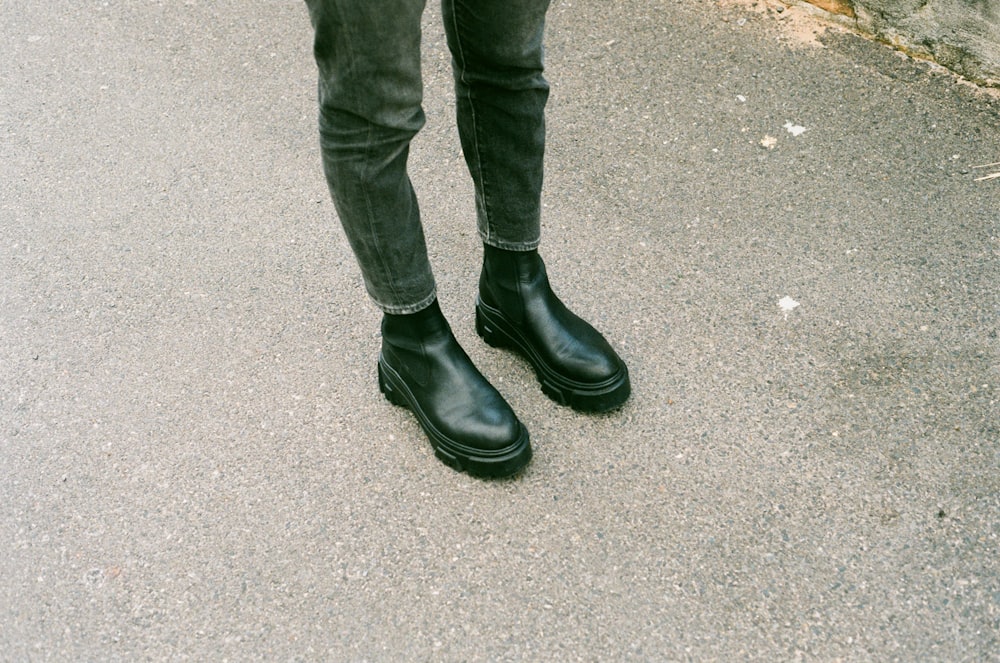 person in black pants and black leather boots