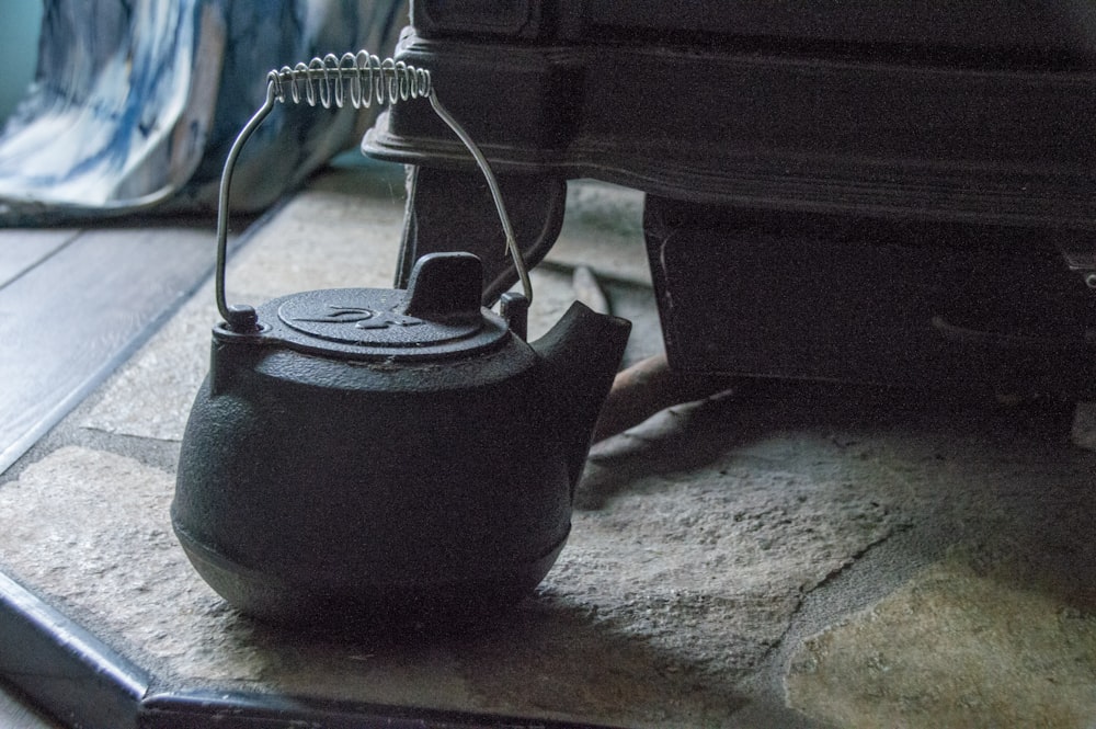 a kettle sitting on the ground next to a car