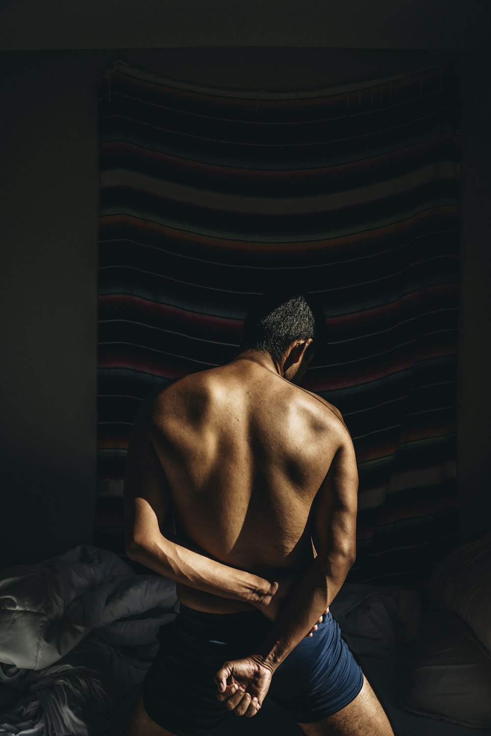 topless man sitting on bed