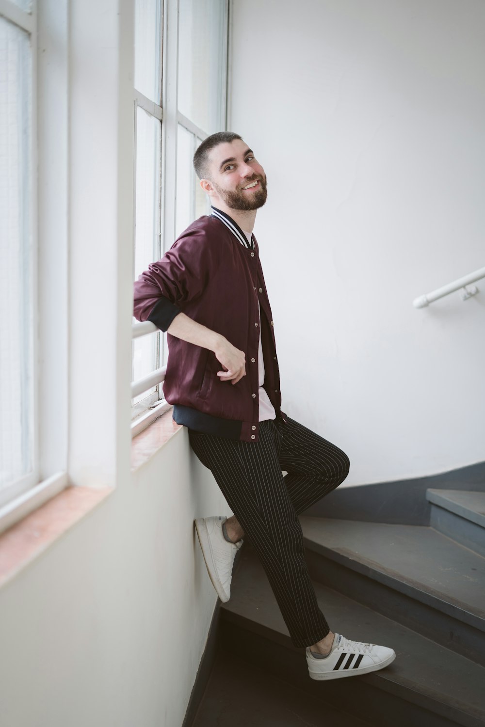 a man leaning against a wall next to a window