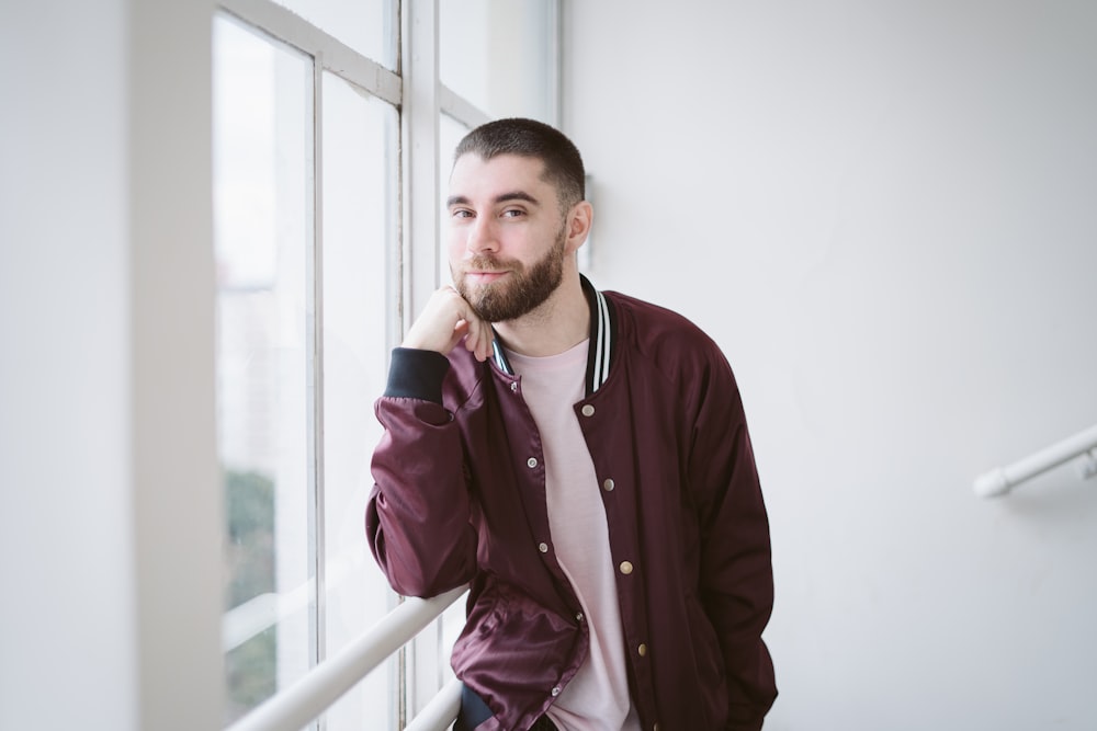 a man leaning against a wall next to a window