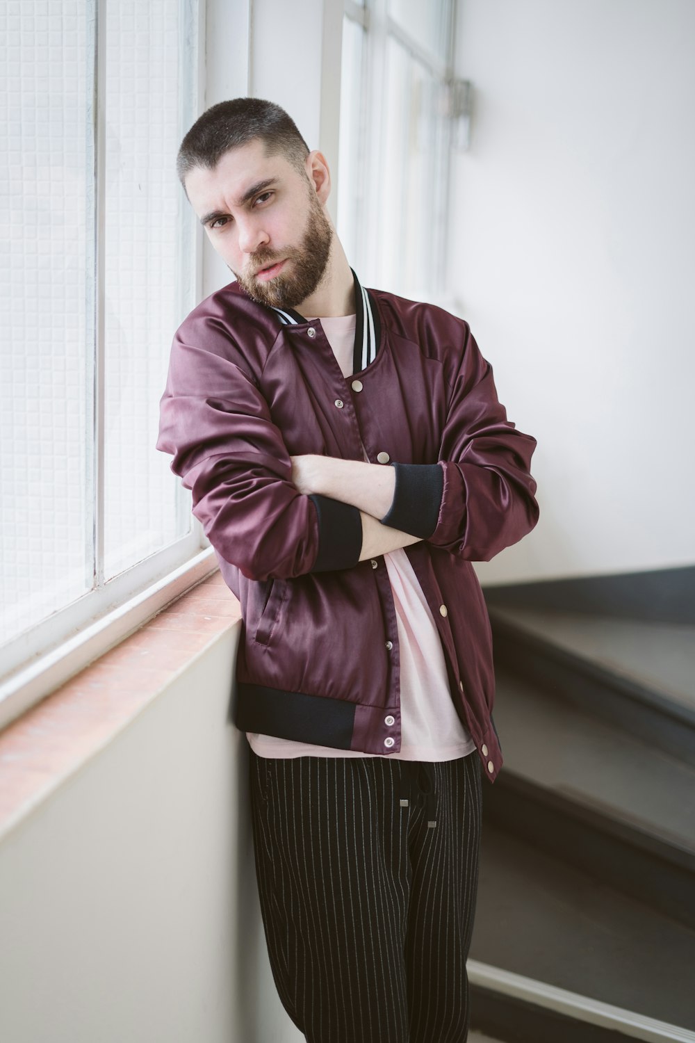 a man with his arms crossed leaning against a wall