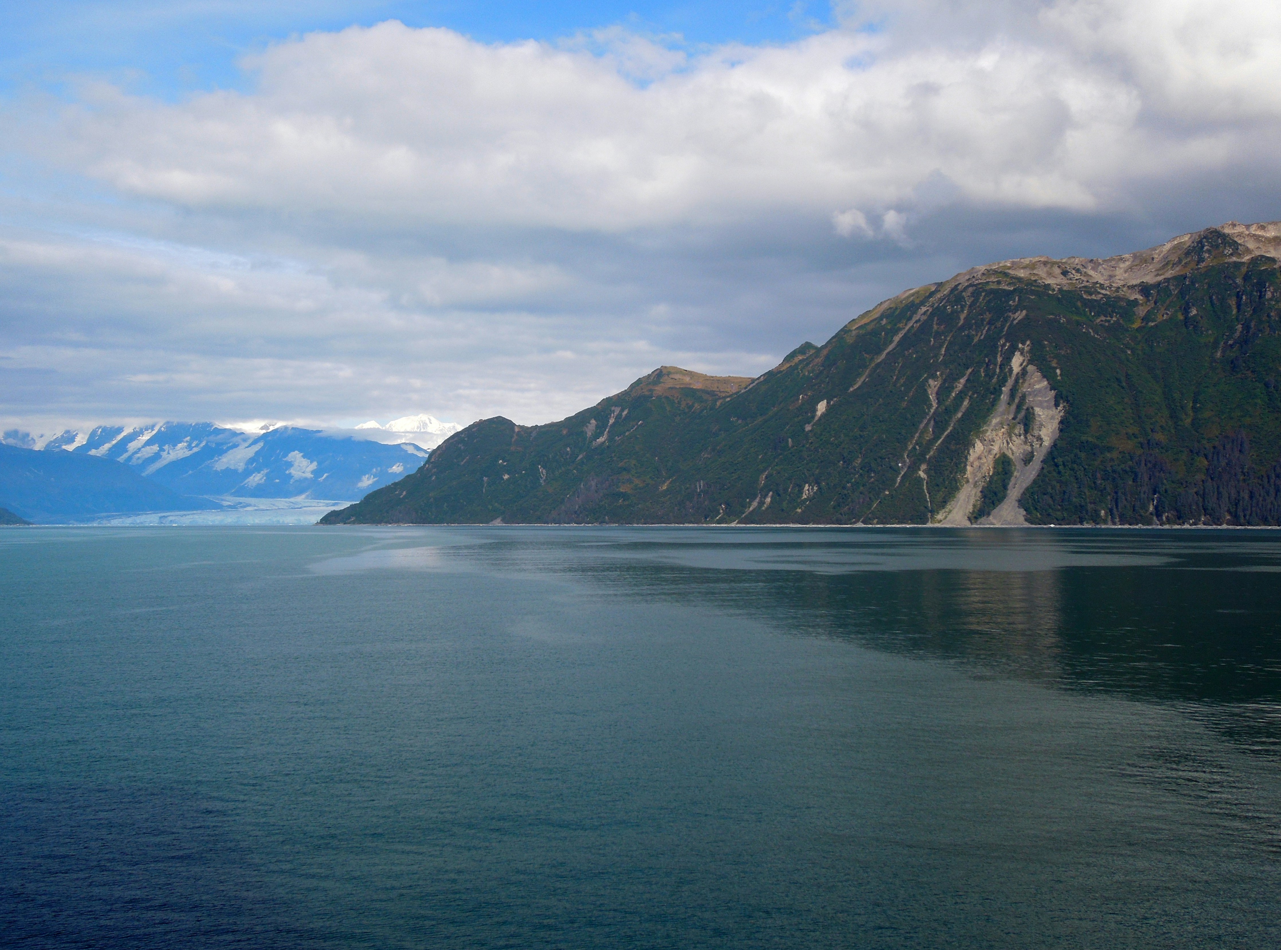 body of water near mountain under white clouds during daytime, 