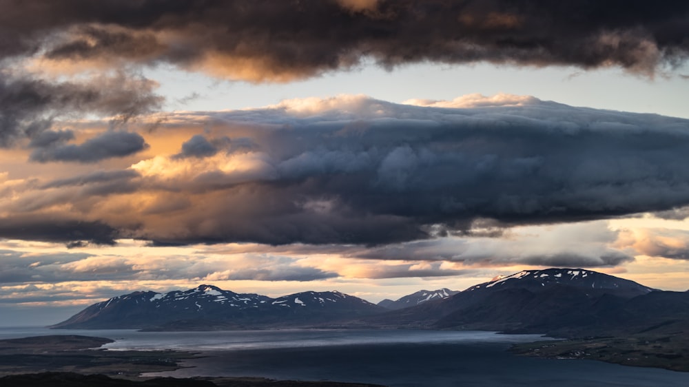 white clouds over snow covered mountains and mountains