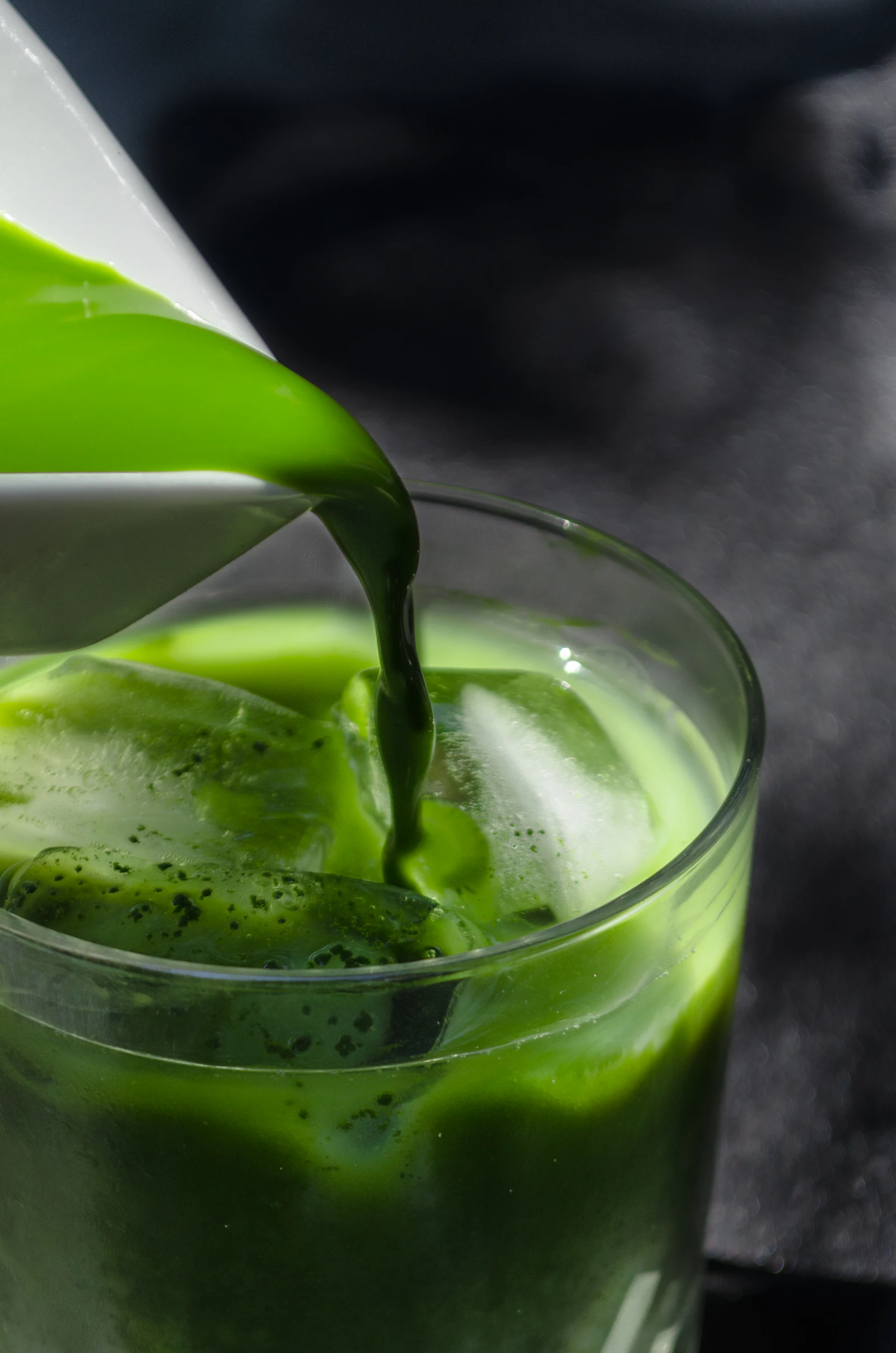 A close up of bright green matcha being poured over ice in a glass