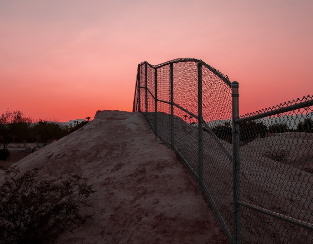 a fence with a sunset in the background