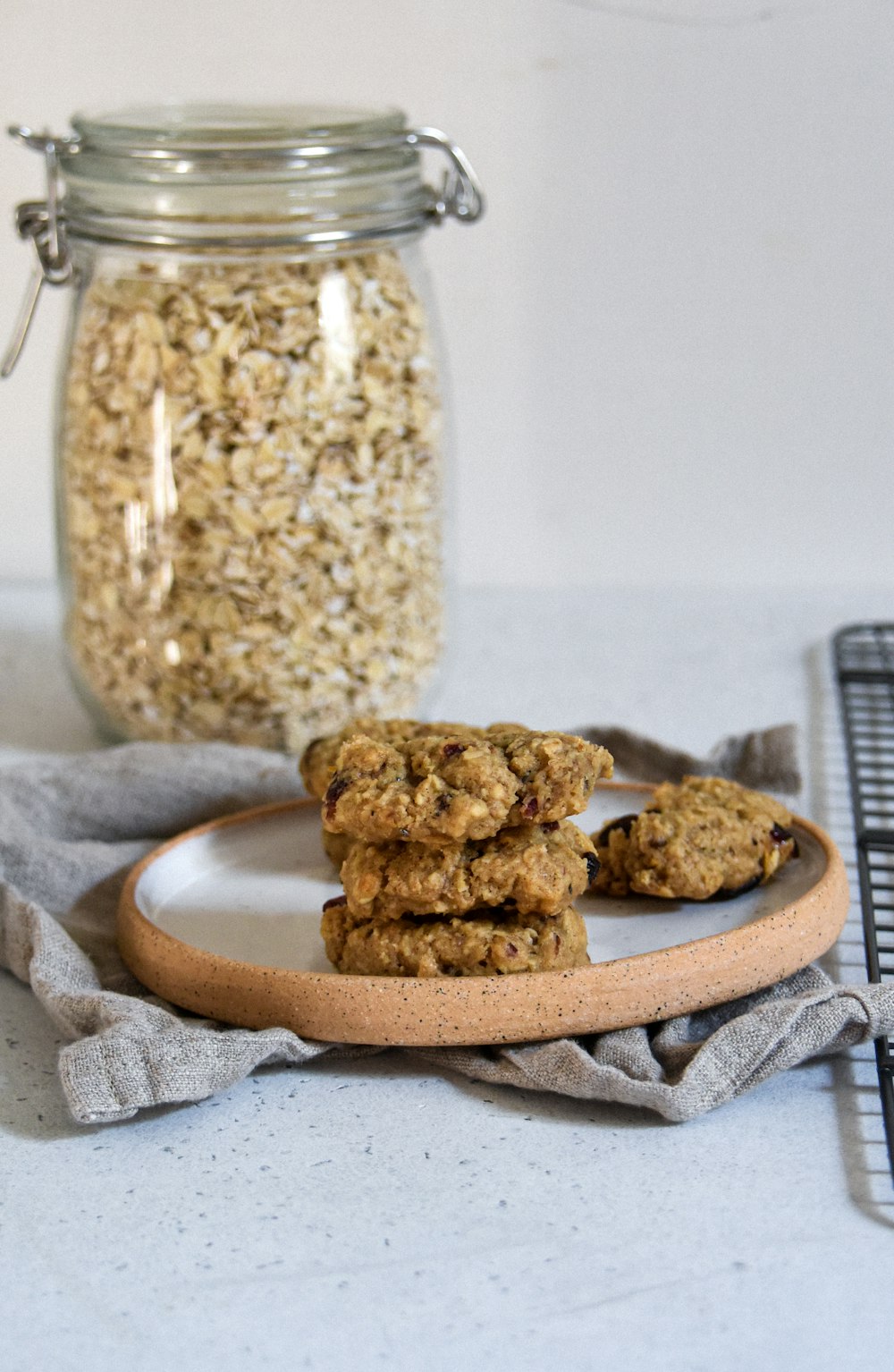 a stack of oatmeal cookies on a plate next to a jar of