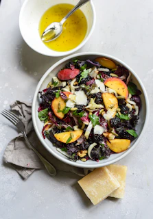 a bowl of salad next to a bowl of dressing