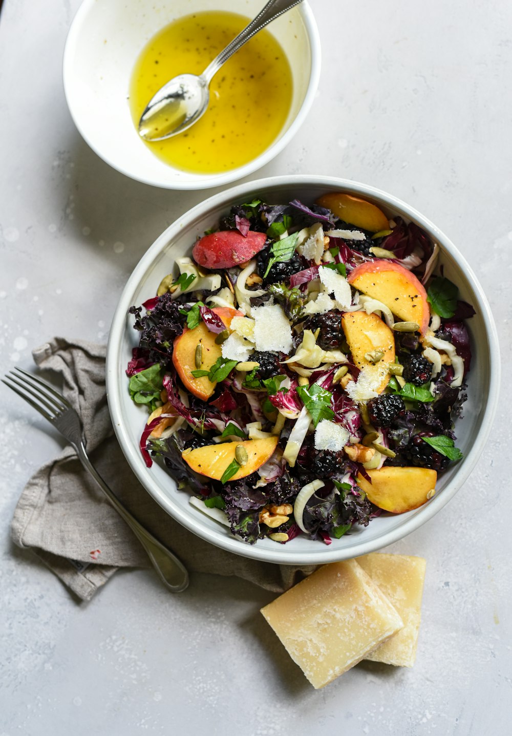 a bowl of salad next to a bowl of dressing