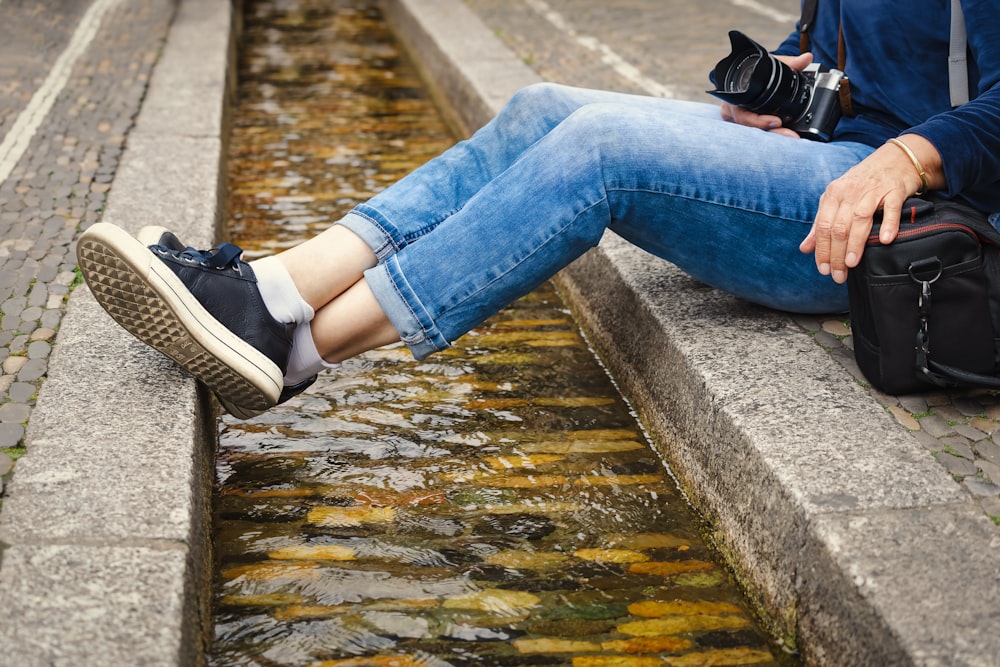 a person sitting on a ledge with a camera