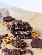a pile of chocolate covered pretzels on top of a piece of parchment paper