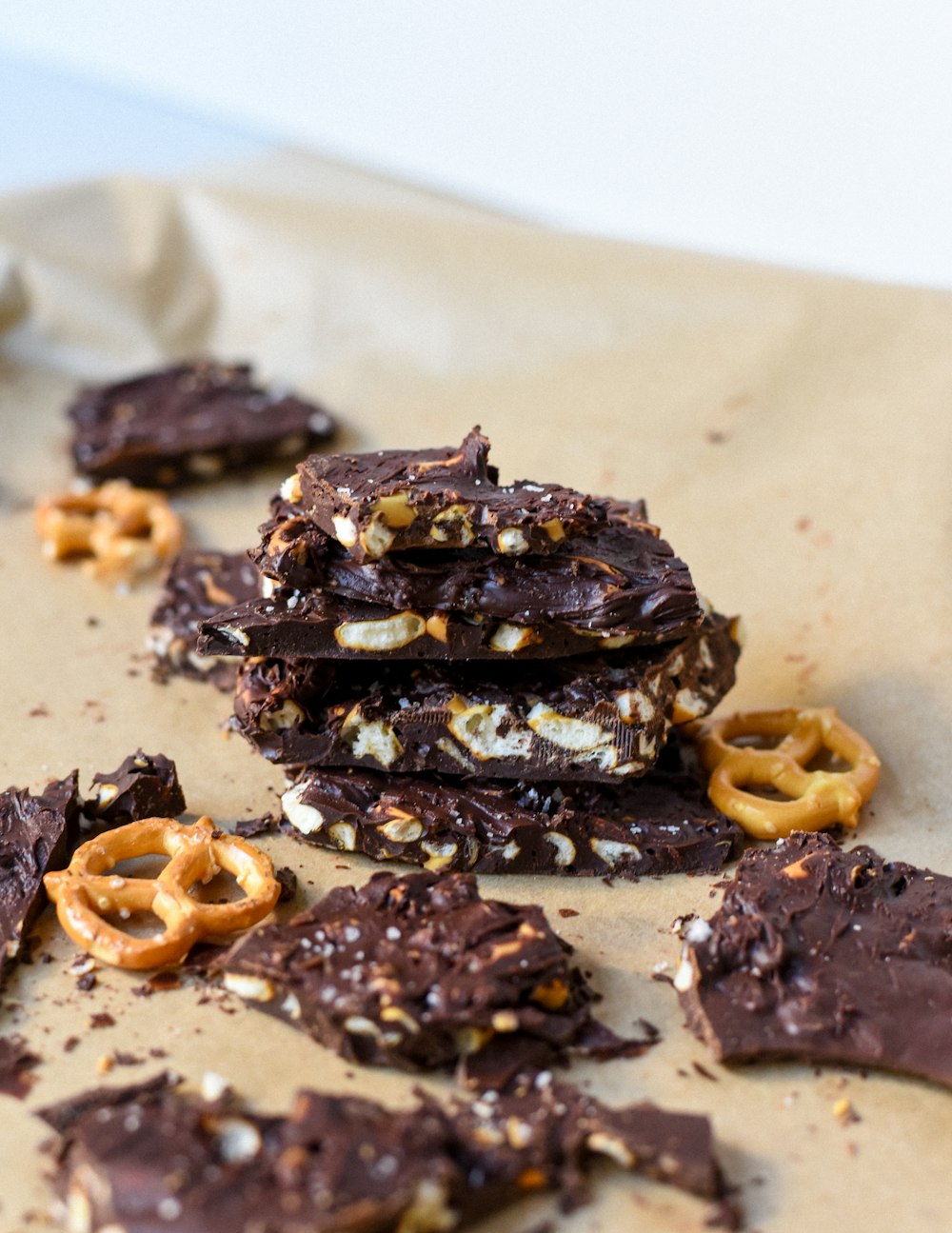 a pile of chocolate covered pretzels on top of a piece of parchment paper