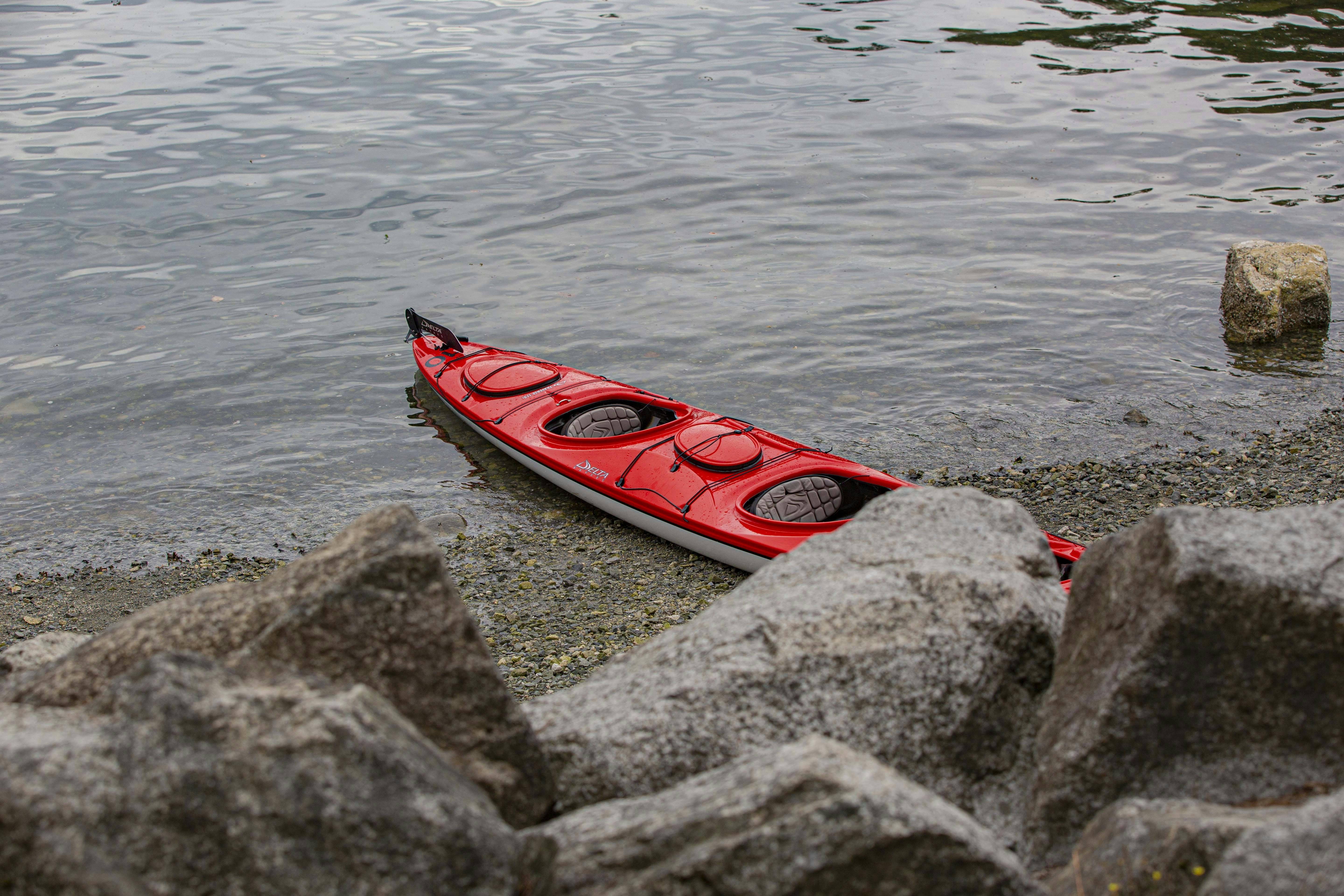 a red kayak sitting on the shore of a lake