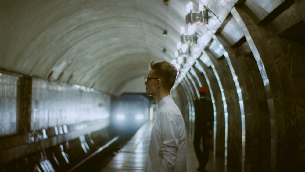 man in white dress shirt standing on train station