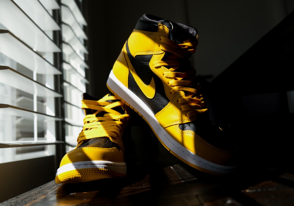 a pair of yellow and black sneakers sitting on a window sill
