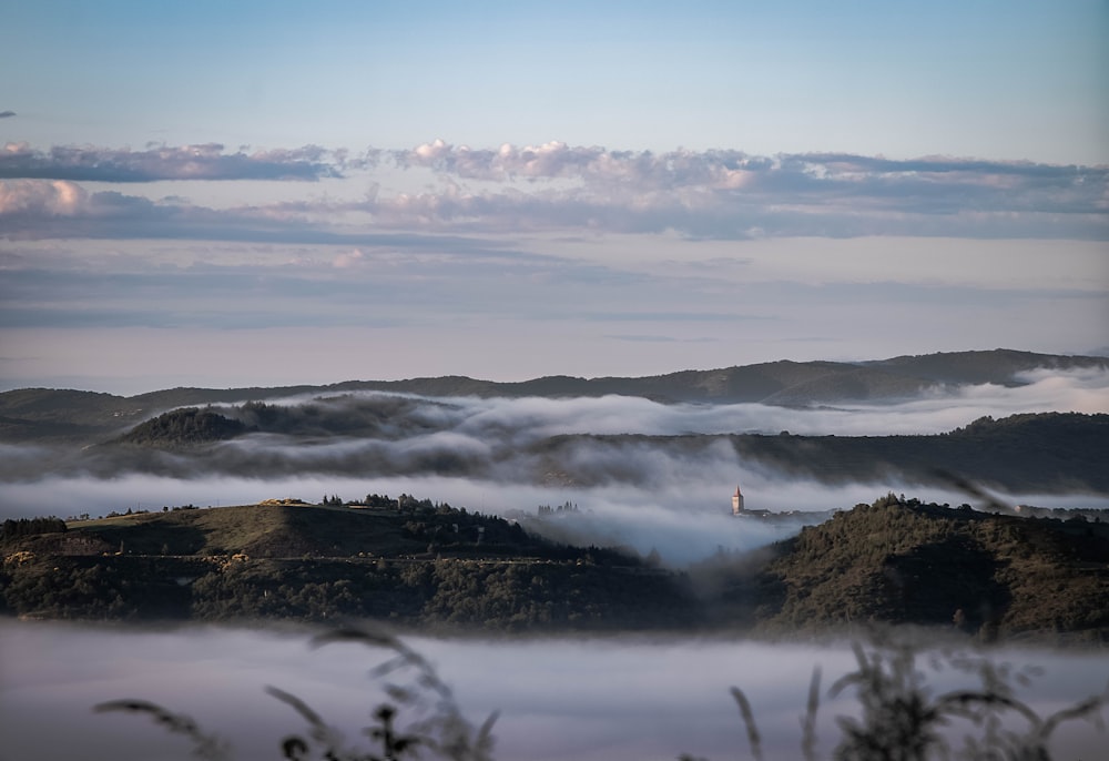 a foggy landscape with a lighthouse in the distance