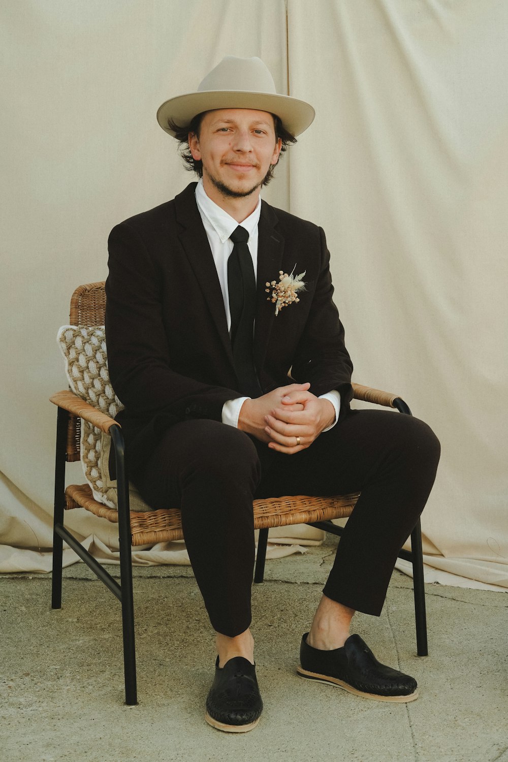 man in black suit sitting on brown wooden armchair
