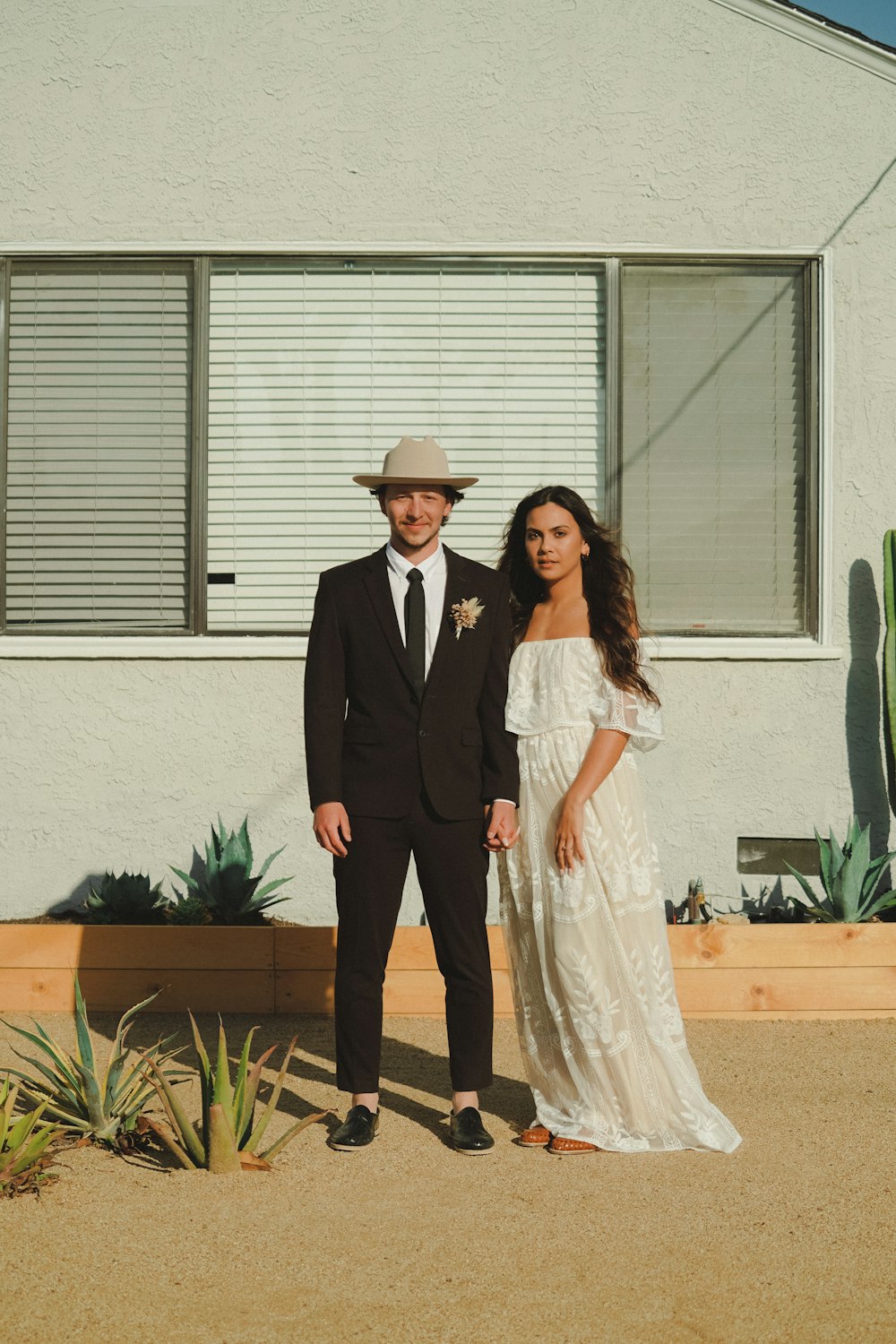 man in black suit standing beside woman in white dress