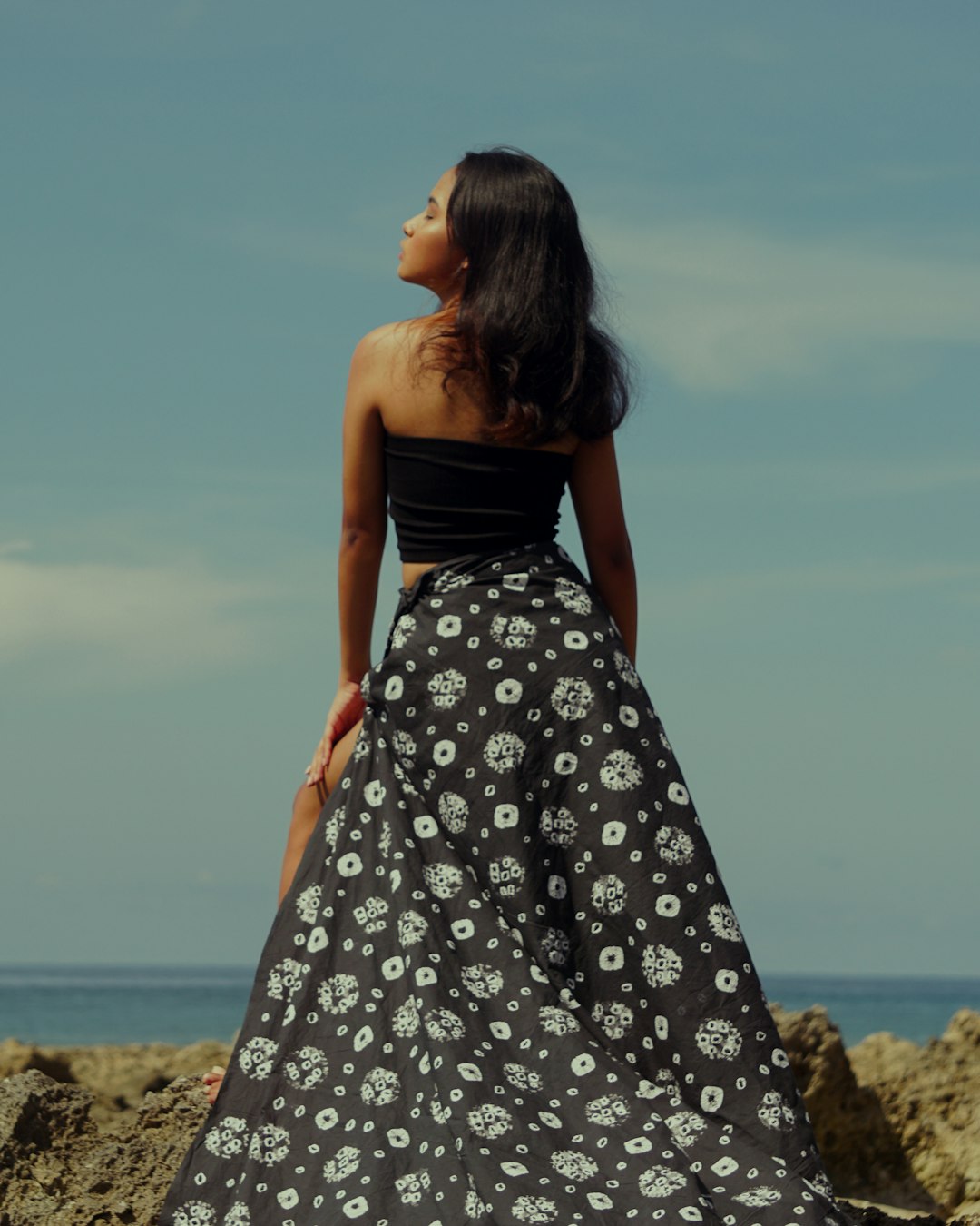 woman in black and white floral tube dress standing on brown sand during daytime