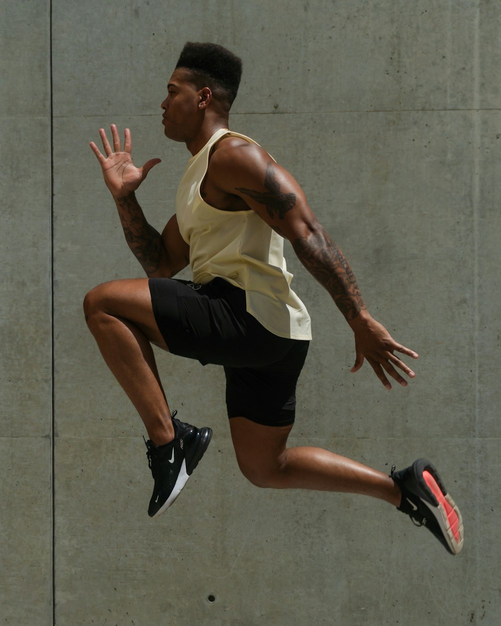 man in white tank top and black shorts jumping on gray concrete floor