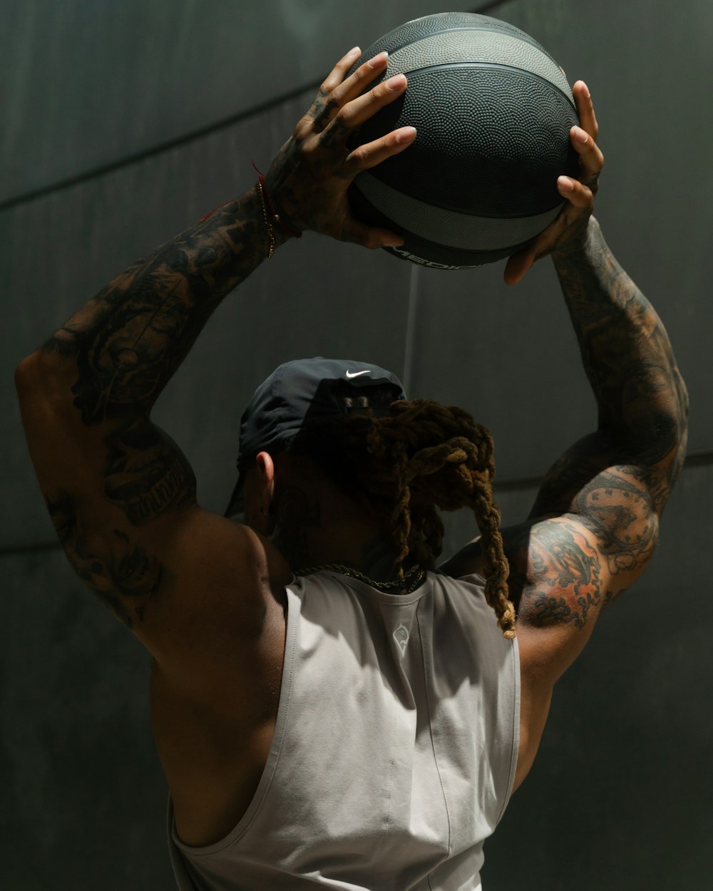 man in white tank top holding black basketball