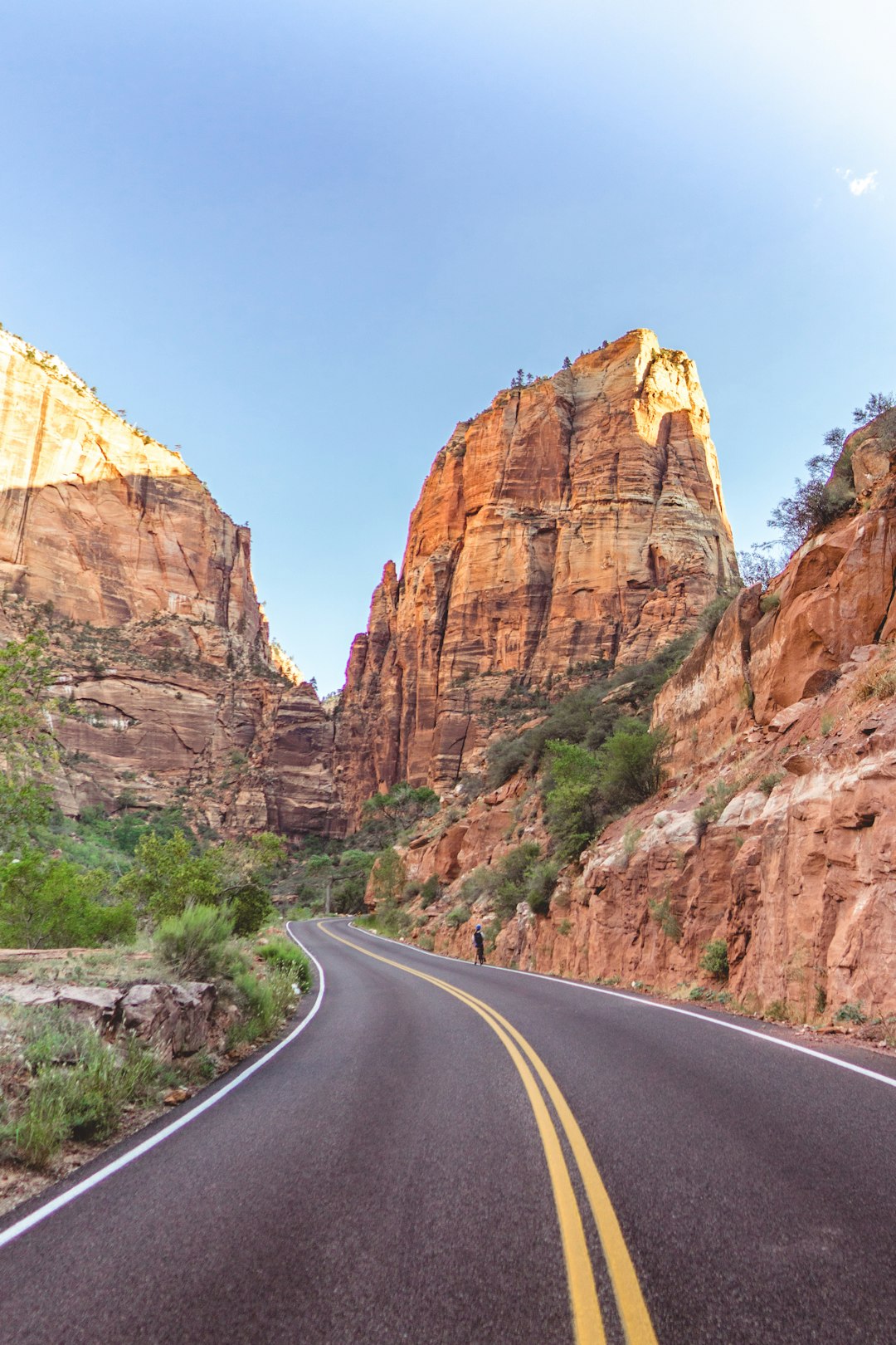 gray asphalt road between brown rock formation during daytime