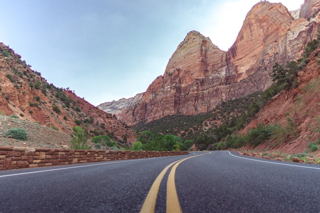 gray concrete road near brown rocky mountain during daytime