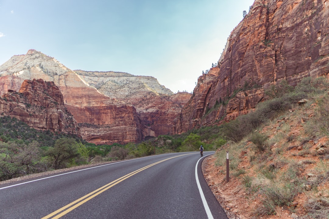 person walking on road near brown rock formation during daytime