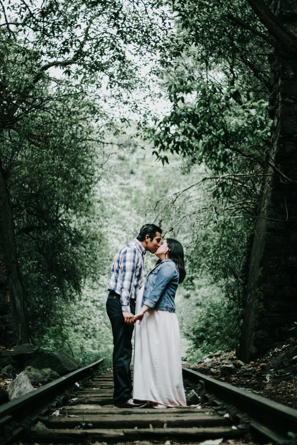 man and woman kissing in the woods during daytime