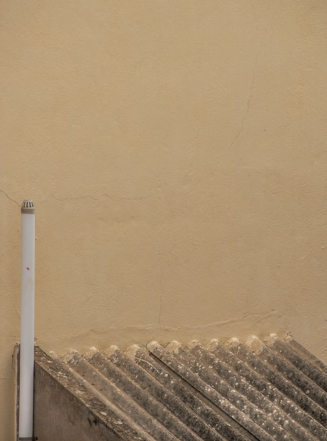 white metal pipe near brown wall