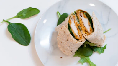 Grilled chicken wrap sliced diagonally showing colorful veggies inside.