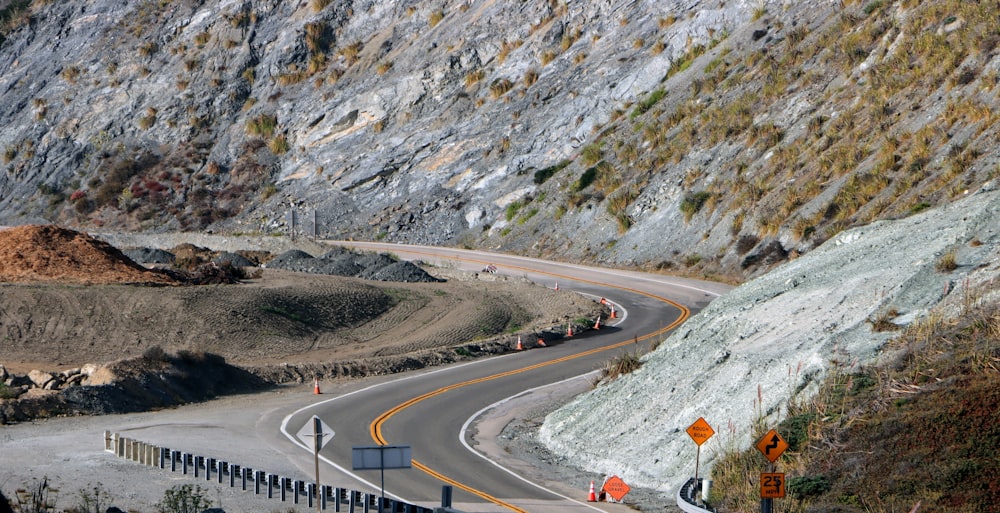 gray concrete road near mountain during daytime