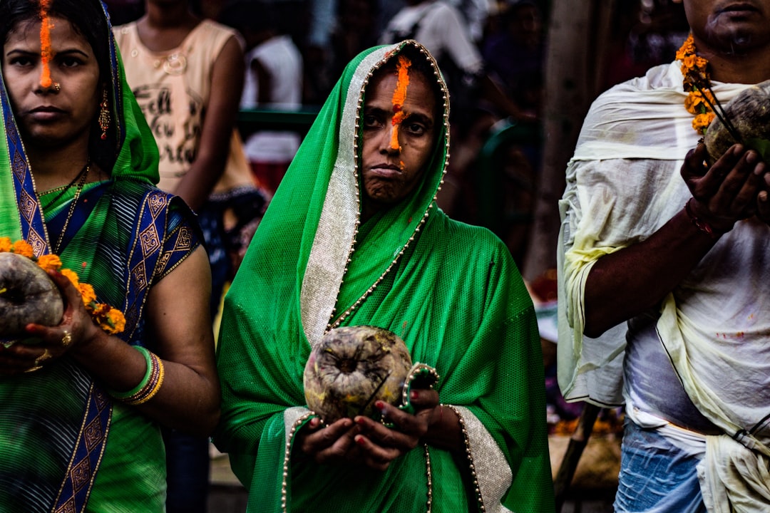 woman in green and brown sari carrying baby