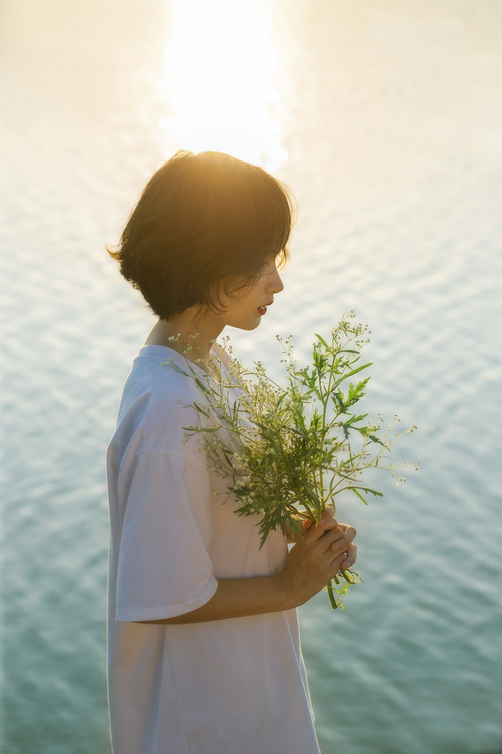 woman in white shirt holding green plant