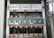 A detailed view of an electrical panel displaying a neatly arranged set of circuit breakers and wiring. The panel includes multiple switches, each labeled with specific codes, and wires of various colors connecting to them. The setup is orderly, with cables aligned and organized through plastic holders.