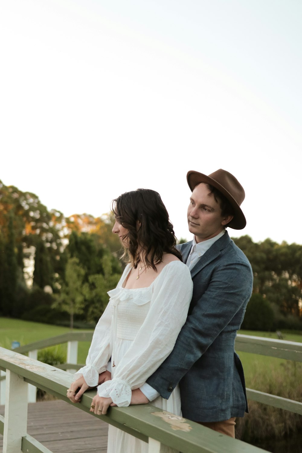 woman in white dress shirt and blue denim jeans sitting on green wooden bench during daytime