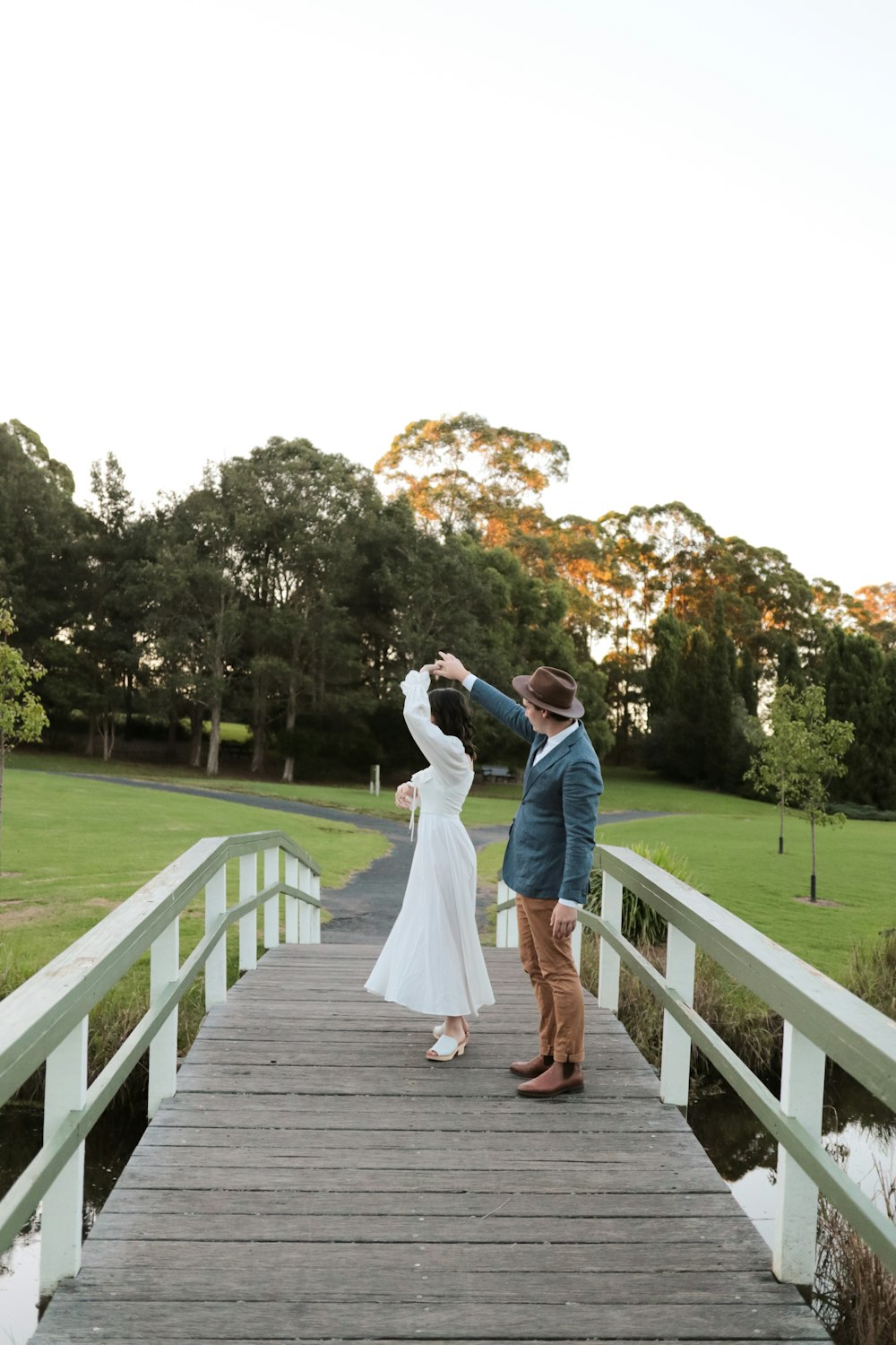 man and woman kissing on brown wooden bridge during daytime