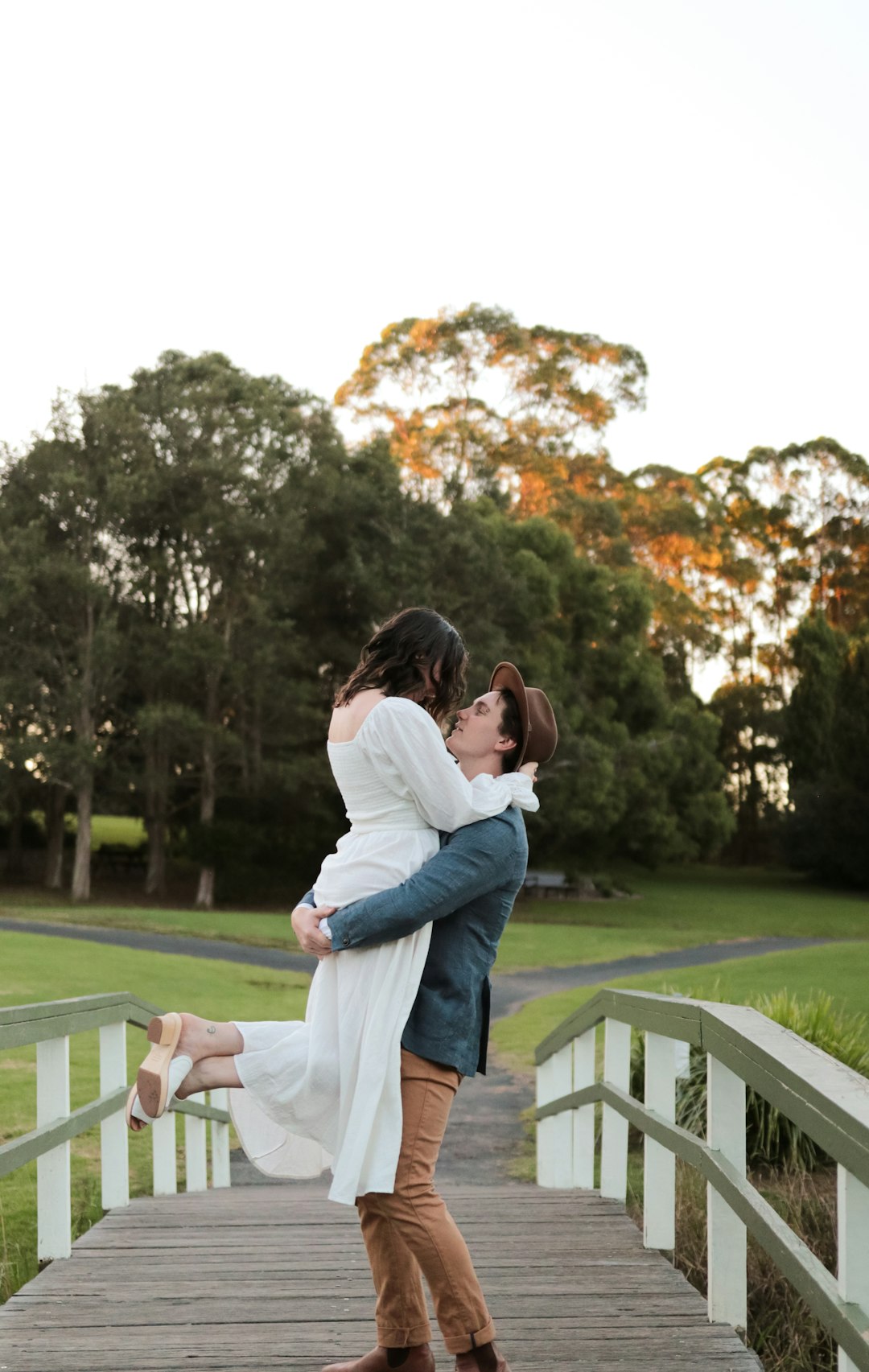 man and woman kissing on white wooden fence during daytime