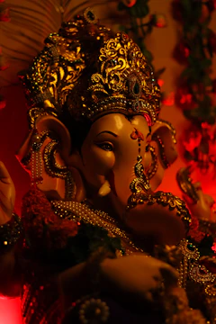 Close-up of a golden Lord Ganesha idol with intricate carvings glowing softly under warm light.