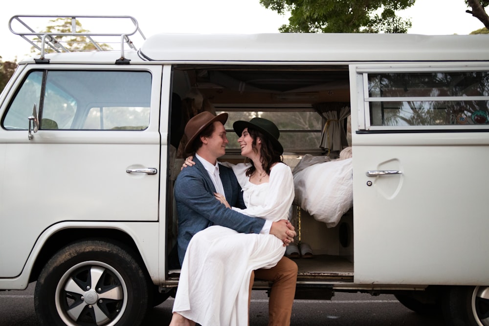 man in blue dress shirt sitting on white van