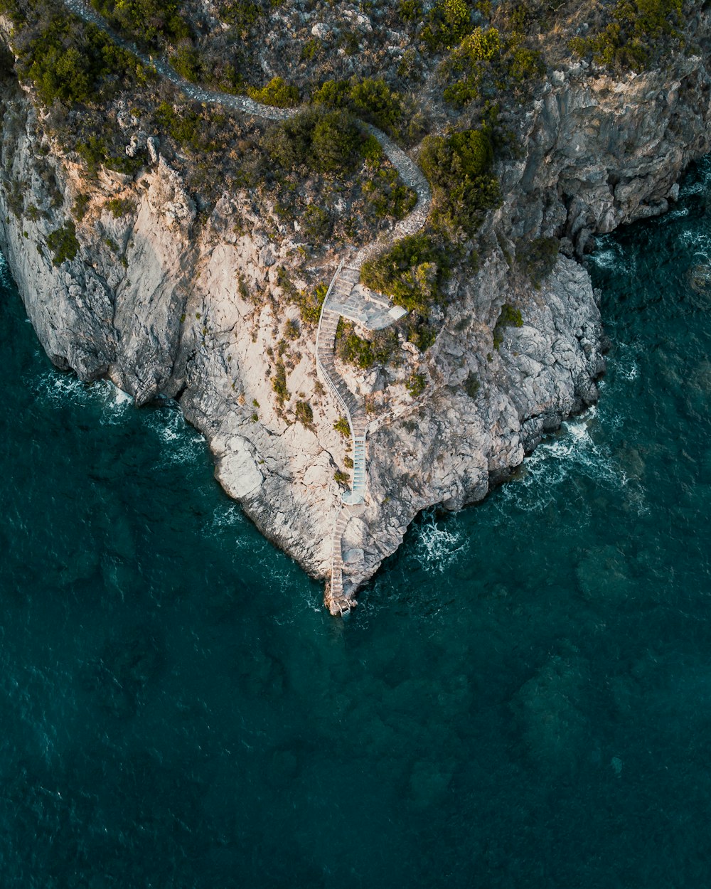 Vista aérea de la montaña verde y marrón al lado del cuerpo de agua durante el día