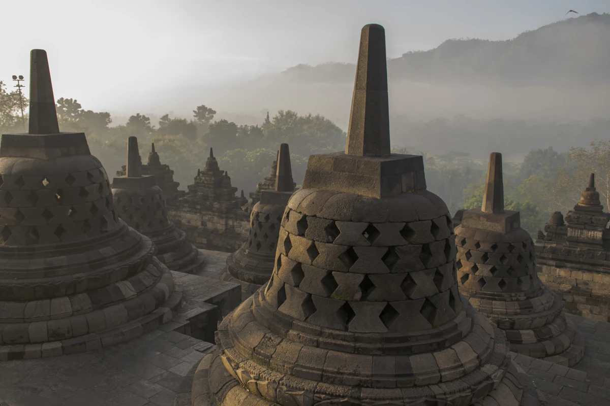 Stone bell-shaped stupas of Borobudur overlooking the tranquil Kedu Plain at dawn