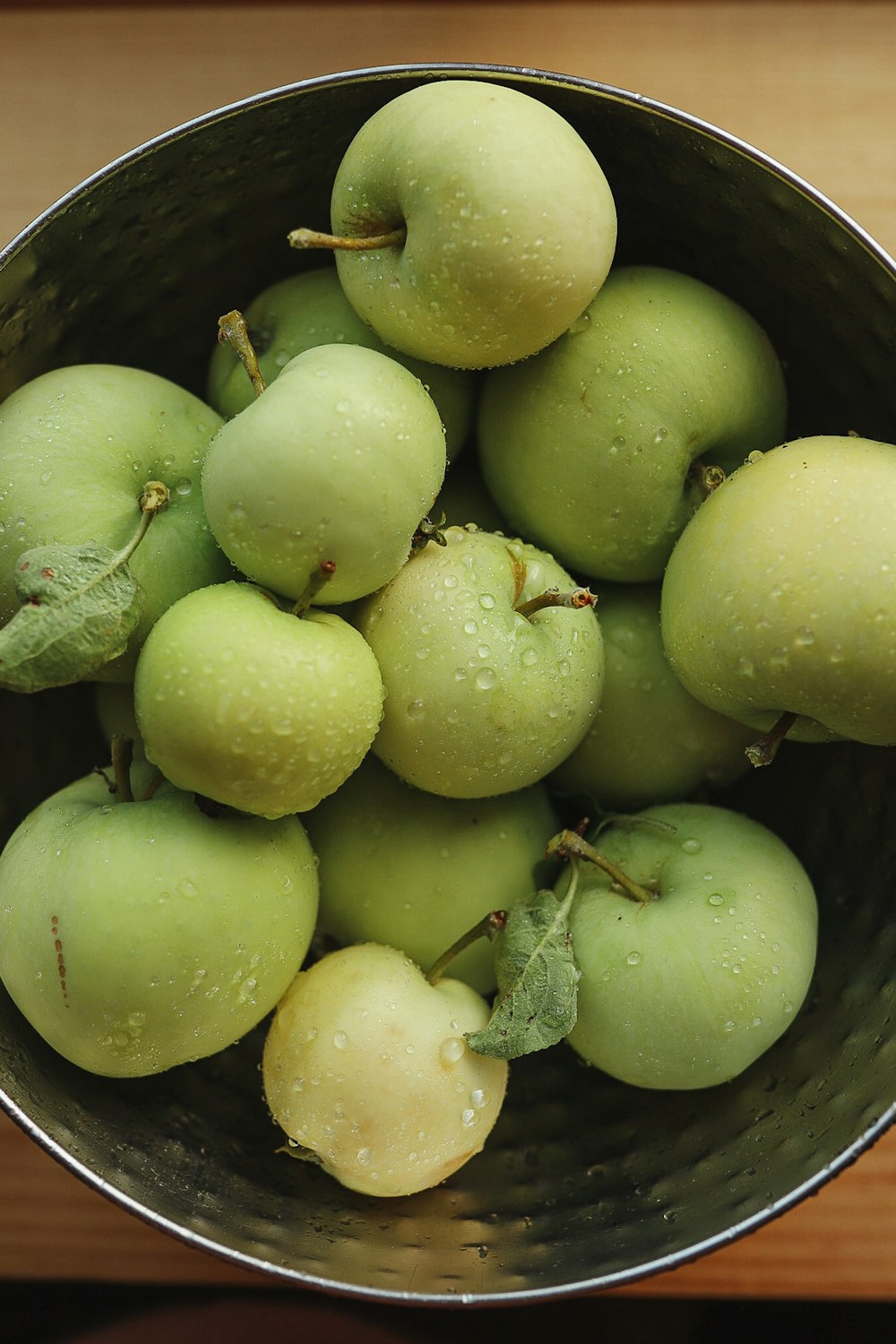 Frutas redondas verdes en cubo de plástico negro