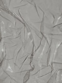 Crinkled and partially transparent plastic sheet, with light reflecting off its surface.