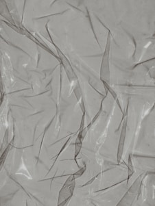 Crinkled and partially transparent plastic sheet, with light reflecting off its surface.