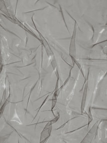 Crinkled and partially transparent plastic sheet, with light reflecting off its surface.