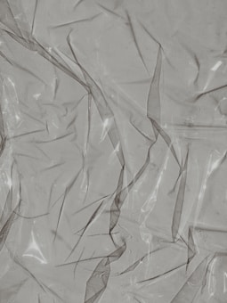 Crinkled and partially transparent plastic sheet, with light reflecting off its surface.